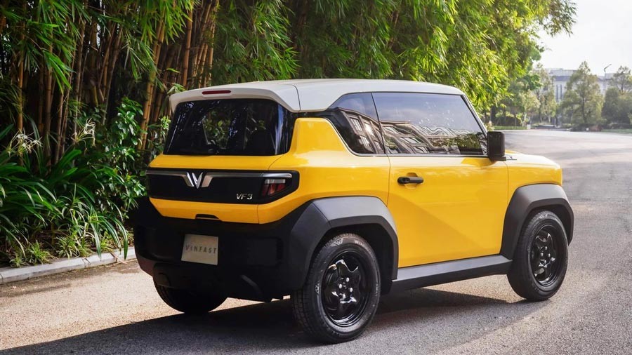 VinFast VF3 màu vàng nhìn từ góc sau giữa hàng tre xanh